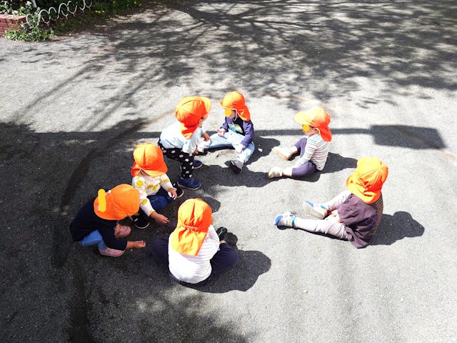 2歳児のおしゃら探検隊が公園で車座になって何やら話し合っています。「今日、クマさん来るかなあ？」