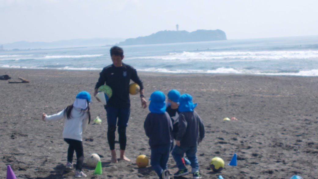 江の島が見える海岸でサッカー